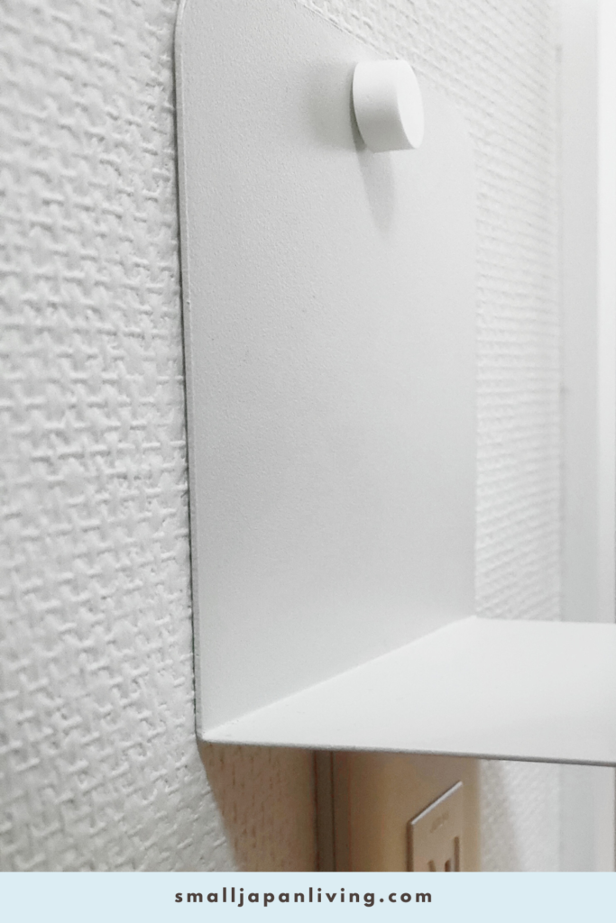 Side view of a bookend wall shelf phone charging setup above a wall outlet, showing how the space-saving charging station is positioned in a small apartment