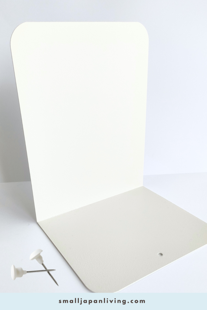 Minimal DIY materials for a bookend phone charging shelf hack, including a bookend, wall hooks, and a charging cable for small space organization